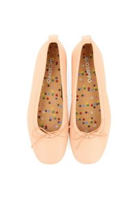 Zapatos planos de color durazno con una parte superior sintética suave, punta redondeada y un adorno de lazo. La plantilla presenta un patrón de estrellas multicoloras.
