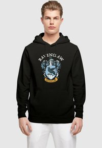 Svart hettegenser med et Ravenclaw-emblem i blått og gull, med intrikate detaljer og en frontlomme. Lange ermer med ribbestrikkede cuffs.