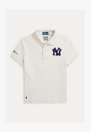 Valge lühikeste varrukatega polosärk, mille rinnal on tumesinise New York Yankeesi logo ja varrukal ning äärel õmmeldud Ralph Laureni logo.