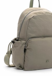 Vaaleanharmaa nailonreppu, jossa on sileä pinta, kaksoisvetoketjulliset taskut ja säädettävä hihna, tunnettu minimalistisesta muotoilustaan.