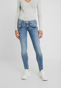 Smala jeans i ljusblå denim med blekningar. Har fem fickor, kontrasterande sömmar och en dragkedja med knappstängning.