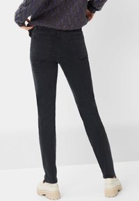 Zwarte skinny jeans van denim, met een hoge taille, twee achterzakken en een nauwsluitende snit, gecombineerd met beige plateau schoenen.