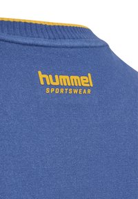 Niebieska koszulka sportowa z bawełny z żebrowanym kołnierzykiem w żółtych akcentach. Z tyłu znajduje się napis "hummel SPORTSWEAR" w żółtym kolorze.