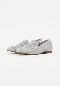 Hallid hallid slip-on kingad, millel on tekstuuriga kudumipinna ülemine osa, elastsed külgdetailid ja lame, heleda pruuni tallaga. Kujundatud mugavuse ja hingavuse tagamiseks.