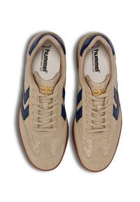 Beige sneakers with navy accents, suede and textile materials, textured patterned sides, flat laces, and a gum rubber sole.