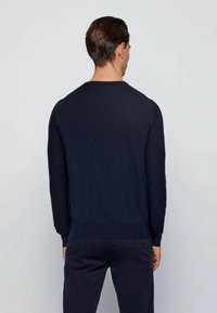 Námořnická modrá pletená svetr s dlouhými rukávy a kulatým výstřihem. Má strukturovaný povrch a žebrované manžety a lem.