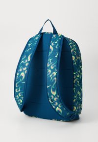 Mochila azul con una superficie texturizada y un vibrante patrón abstracto en verde y amarillo. Cuenta con correas acolchadas y un asa superior para llevarla.