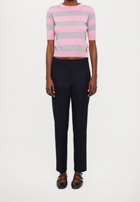 Maglione corto a maniche corte a righe rosa e grigie, abbinato a pantaloni navy su misura e scarpe marrone scuro.