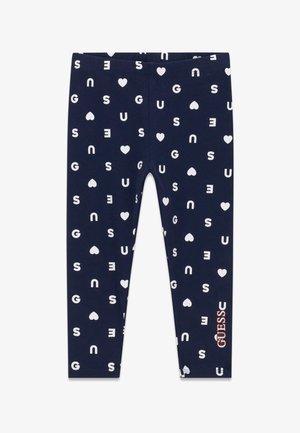 Leggings bleu marine avec des lettres blanches dispersées et des formes de cœur, et un logo rose "GUESS" près du bas de la jambe droite.