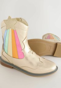 Botas de tobillo metálicas doradas con un acento de estrella, que presentan paneles a rayas de colores en rosa, azul y verde. Suela de goma con un diseño patternizado.