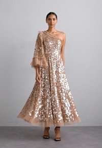 En knælang, en-skulder kjole i nude stof med sequin pynt, der har lagdelte tylruffler på den ene ærme.