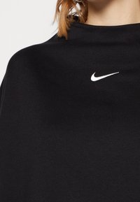 Svart bomulls sweatshirt med en strukturerad hals och en liten vit Nike-logotyp på bröstet. Slät textur med en avslappnad passform.