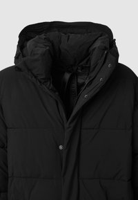 Schwarze Pufferjacke mit hohem Kragen, Knopfverschluss und gesteppten Abschnitten. Weiche, glatte Textur mit einer Kapuze und sichtbarer Innenauskleidung.