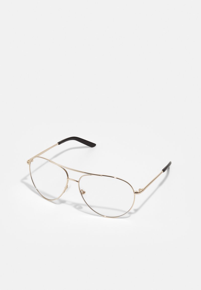 Óculos de metal dourado com formato oval, armação fina e ponteiras pretas. Lentes transparentes com design minimalista e almofadas de nariz ajustáveis.