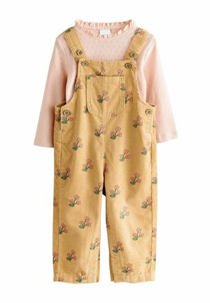 Pantalones de tirantes de pana amarilla con estampado floral, que incluyen un bolsillo cuadrado, tirantes ajustables y una blusa de manga larga rosa con un cuello con volantes.