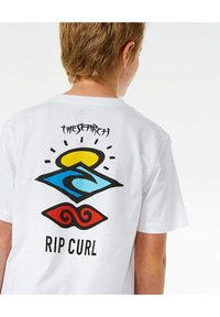 T-shirt en coton blanc avec des graphiques colorés au dos : un soleil jaune, des vagues bleues et des tourbillons rouges avec le texte "RIP CURL" en dessous.
