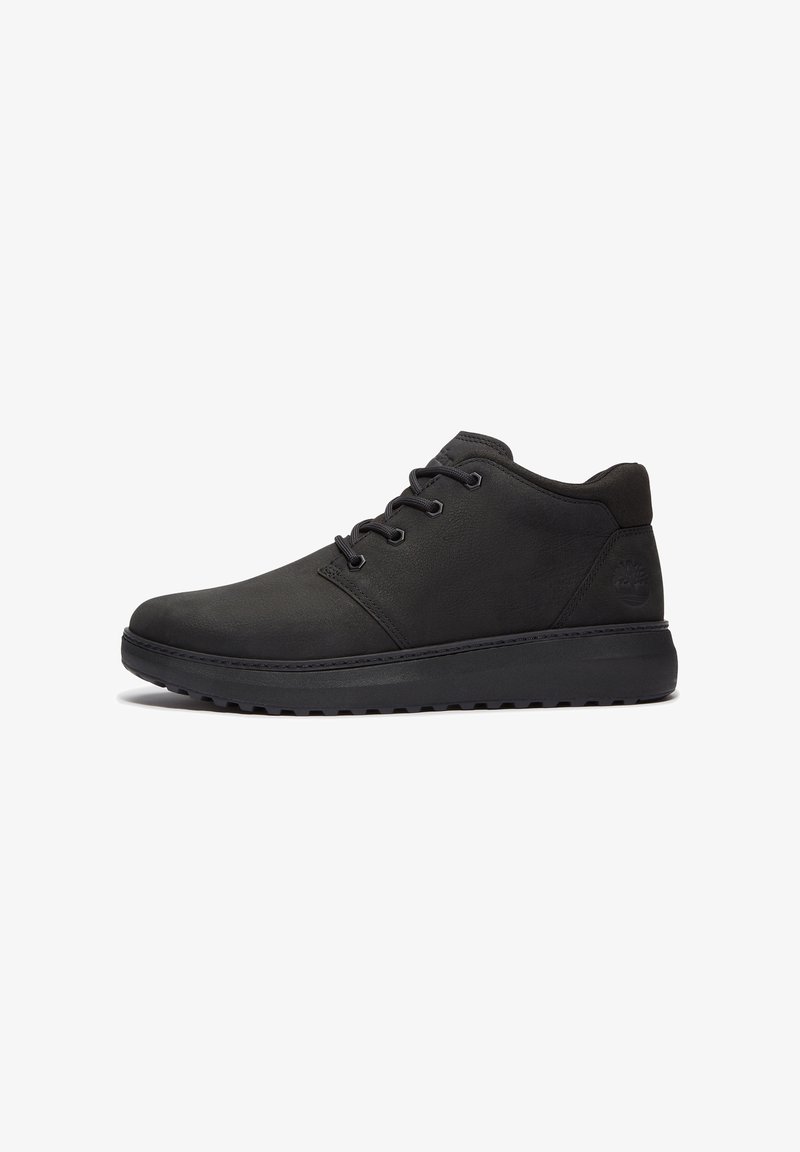 Bottine noire en cuir avec fermeture à lacets, col rembourré et semelle épaisse en caoutchouc texturé, présentée de profil sur fond blanc.