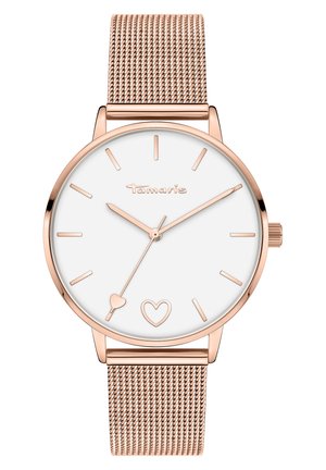 Montre ronde avec un cadran blanc, des aiguilles en acier rose et un détail en forme de cœur. Elle est dotée d'un bracelet en mailles roses et d'une lunette polie.