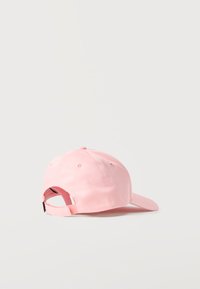 Ανοιχτό ροζ καπέλο μπέιζμπολ με ρυθμιζόμενο λουράκι, που βρίσκεται πάνω σε ανοιχτή επιφάνεια, απεικονίζεται από την πίσω δεξιά πλευρά.