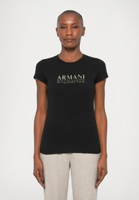 Tricou negru cu mânecă scurtă, cu guler rotund, având un logo auriu "ARMANI EXCHANGE" imprimat pe față. Material neted.