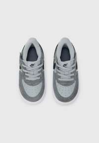 Sivé semišové tenisky s mesh akcentmi, svetlosivými prekrytiami a čiernym logom Swoosh. Majú perforovanú špičku a sivé šnúrky. Biela gumová podrážka.