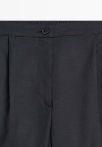 Zwarte geplooide broek met een gladde textuur, voorzien van een tailleband en een enkele knoopsluiting. Zijzakken geïntegreerd in het ontwerp.