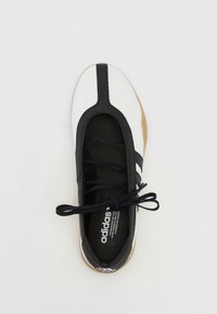 Sapatilha atlética em preto e branco com um design elegante, sola em borracha, parte superior texturizada e atacadores pretos. Marca visível na palmilha.