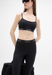 Zwarte sport bralette en bijpassende high-waisted legging, beide van een zachte, rekbare stof en voorzien van merk elastieken.