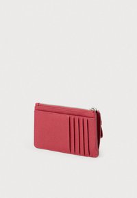 Červená kožená peňaženka s textúrovaným povrchom, vybavená zipsovým zatváraním a viacerými priehradkami na karty z jednej strany pre lepšiu organizáciu. Kompaktný dizajn.