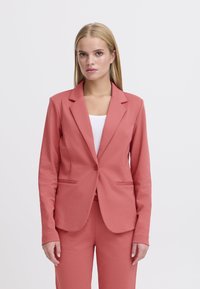 Koraalroze blazer met een geknipte revers, enkele knoopsluiting en opgestikte zakken. Soepele, rekbare stof met een getailleerde pasvorm.