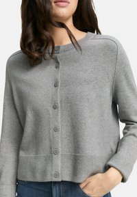 Grauer Cardigan mit rundem Halsausschnitt, fünf Knöpfen auf der Vorderseite, gerippten Bündchen und Saum, aus einem weichen, strukturierten Stoff.