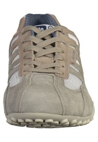 Scarpa sportiva in suede grigia con pannelli in rete, accenti beige a contrasto, punta arrotondata e suola testurizzata con motivi di battistrada circolari.