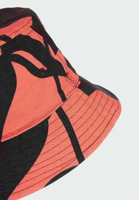 Bucket hat in coral and black fabric, featuring a wide brim, distinct pattern, stitched accents, and eyelet ventilation detail.