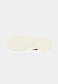 Λευκή σόλα παπουτσιού από καουτσούκ με υφή στην επιφάνεια, εργονομικό σχήμα και ελαφριά ανύψωση στην περιοχή των δαχτύλων. Διαθέτει λογότυπο στην περιοχή της φτέρνας.