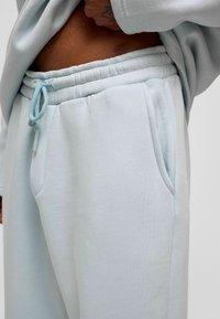Lichtblauwe sweatpants gemaakt van zachte stof, met een elastische tailleband met trekkoord, zijzakken en een ontspannen pasvorm.
