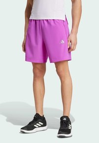 Roosa sportlikud lühikesed püksid elastse vöökohtaga, küljetaskud ja hõbedane Adidas'i logo. Ühendatud mustade sportlike kingadega, millel on valged triibud.