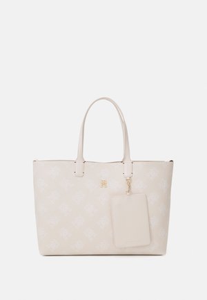 Beige Tragetasche aus synthetischem Material, mit einem sich wiederholenden Logo-Muster, zwei Griffen und einem abnehmbaren passenden Gepäckanhänger. Goldene Akzente.