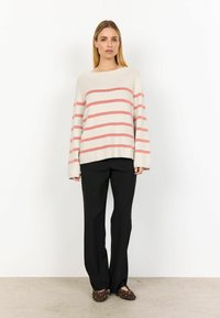 Light beige sweater with pink stripes, loose fit, boat neckline. Paired with black, straight-leg pants and dark brown, studded slip-on shoes.
