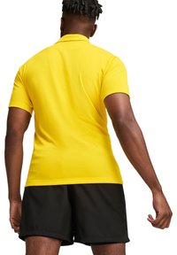 T-shirt met korte mouwen in felgele stof, met een gestructureerd ontwerp. Gecombineerd met zwarte shorts, gezien van achteren.