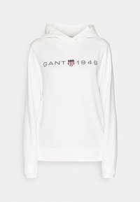 Sudadera blanca con capucha hecha de tejido suave. Presenta un logo frontal "GANT 1949" en negro con un pequeño emblema de escudo multicolor. Mangas largas.