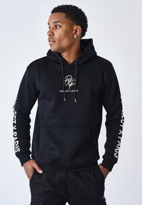 Sudadera negra con bolsillo canguro, cordones y logo blanco "PROJECT X PARIS" en el pecho y las mangas. Fabricada con una tela suave.