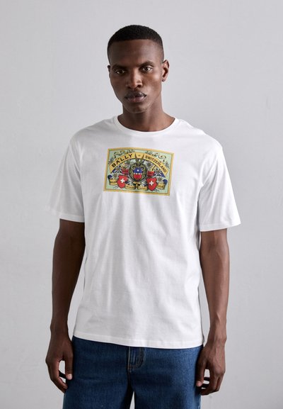 T-shirt en coton blanc avec une impression graphique colorée contenant le texte "BALLY SUISSE", entouré de motifs floraux et d'emblèmes.