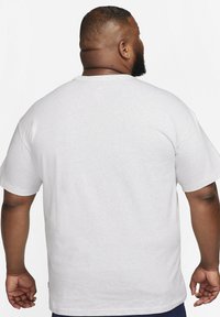 Witte katoenen T-shirt met een klassieke ronde hals, korte mouwen en een relaxte pasvorm. Textuurstof met subtiele stikdetails aan de zoom.