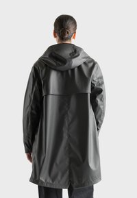 Long black waterproof coat with a hood, adjustable back panel, and seamless design. Features a smooth texture and minimalistic style.