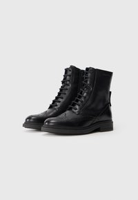 Black leather ankle boots featuring a round toe, lace-up front, embossed detailing, and a low block heel.