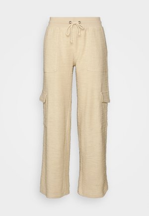 Beige wide-leg cargo pants with a textured fabric, drawstring waist, two front pockets, and one side pocket, featuring a relaxed fit.