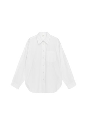 Weißes, langärmliges, übergroßes Hemd mit spitzem Kragen, Frontknopfleiste und einer einzelnen Brusttasche, vor einfachem Hintergrund präsentiert.