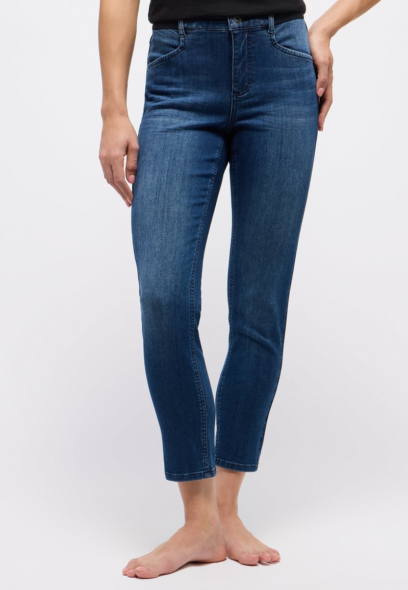 Figurbetonte, knöchellange blaue Jeans aus Denim mit glatter Textur, fünf Taschen und subtiler Ausbleichung am Saum. Klassisches Design mit Knopfverschluss.