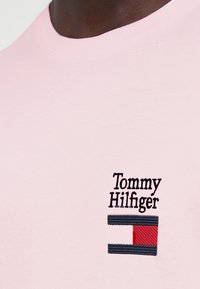 Ανοιχτό ροζ βαμβακερό μπλουζάκι με κεντημένο λογότυπο «Tommy Hilfiger» και ορθογώνιο γραφικό σημαίας σε ναυτικό μπλε, κόκκινο και λευκό.