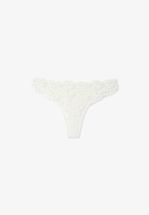 String en dentelle blanche avec un motif floral, des bords festonnés et une texture légère et délicate. Design minimaliste avec un dos en forme de V.